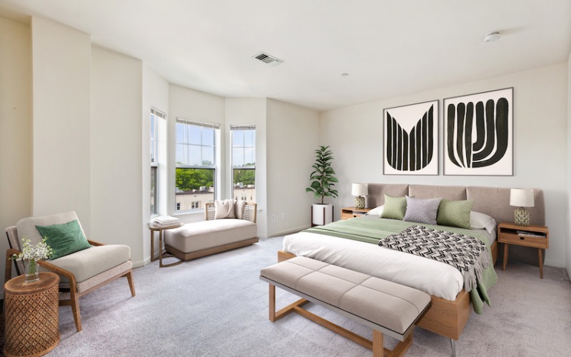 large bedroom with oversized windows, queen bed and seating area
